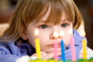 Child looking at the candles on their birthday cake.