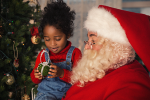 Girl on Santa's lap looking at an ornament.