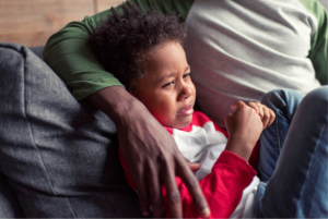 Young boy crying being comforted by his father.