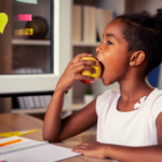 Girl eating healthy after school snack while studying.