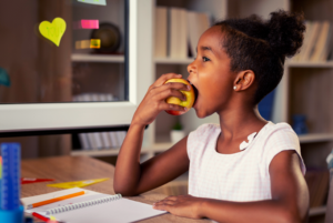 Girl eating healthy after school snack while studying.