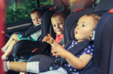 Three children buckled into a back seat.