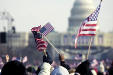 Close up of American flags waving in front of the capitol building.