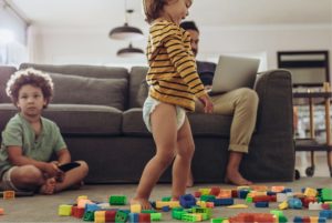 Father working from home while kids play and use device.