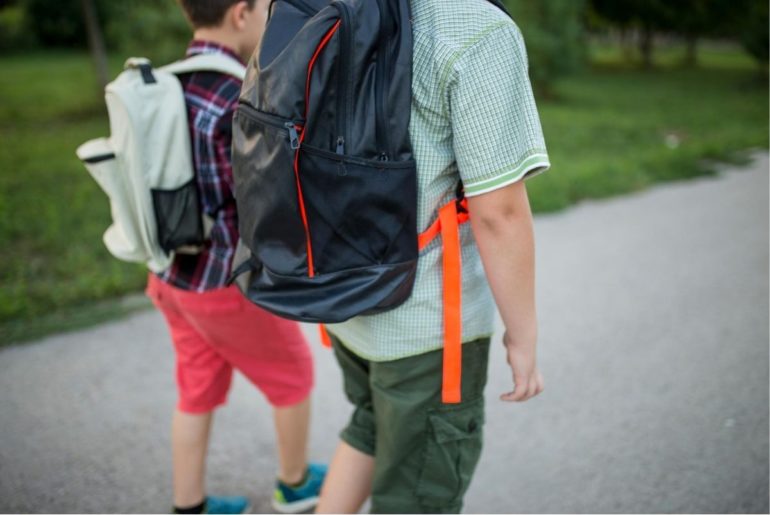 Two boys walking to school with backpacks.