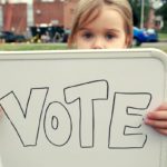 Girl holding sign that says "Vote."