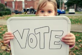 Girl holding sign that says "Vote."