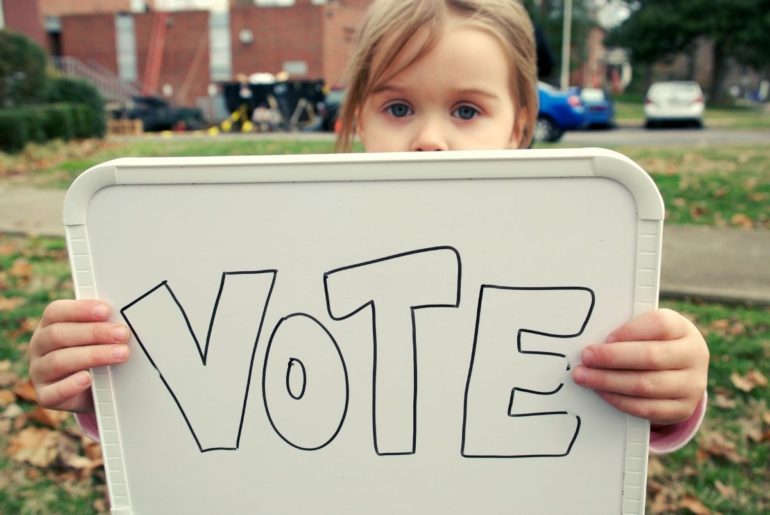 Girl holding sign that says "Vote."