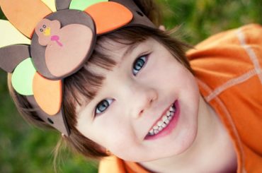 Child wearing turkey headband.