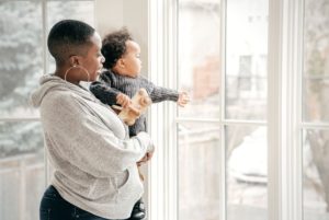 Mother holding toddler pointing out the window.