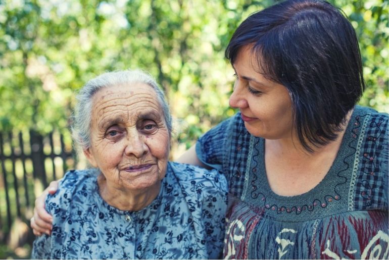 Middle aged woman with aging mother in garden.