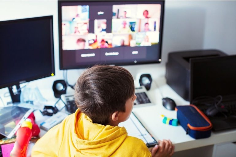 Boy in front of a disorganized desk during remote class time.