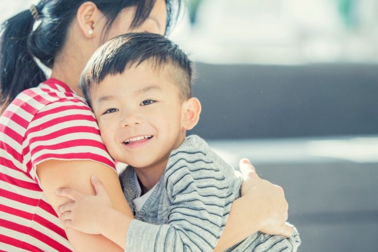 Mother and child hugging and smiling.