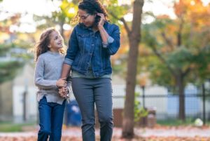 Mother and daughter walking hand in hand outdoors.