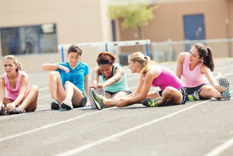 Teens stretching before running on a track.