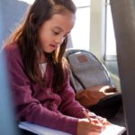 Girl on bus doing schoolwork.