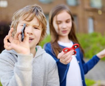 Two children playing with fidget spinners.