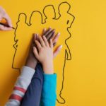 Foster family with hands overlapping on outline of a family drawing.