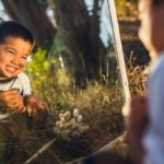 Boy looking in a mirror outdoors.