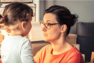 Mom crouched down to talk seriously with young child.