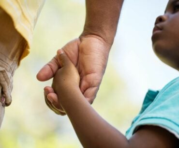 Boy holding dad's hand.