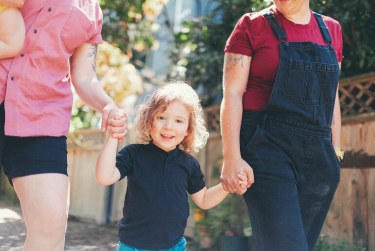 Parents with young child walking outdoors. Addressing unconscious LGBTQ+ biases in your family for a better world for your children.