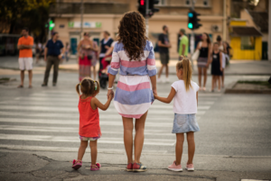 Mother and two children waiting at a crosswalk.