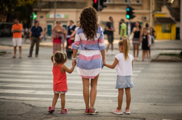 Mother and two children waiting at a crosswalk.