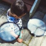 Perspective of adult putting on glasses to see young child.