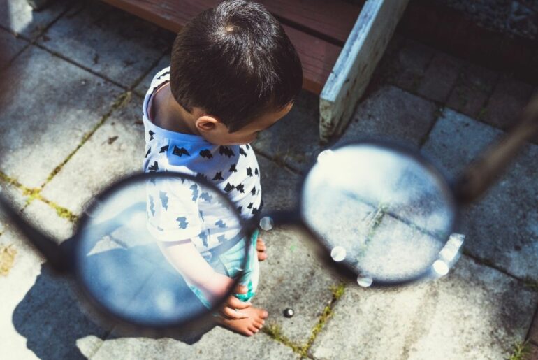 Perspective of adult putting on glasses to see young child.