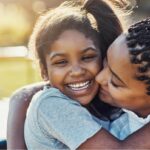 Mother and daughter smiling while hugging.