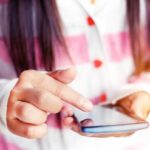 Closeup on teen girls hand using smartphone.