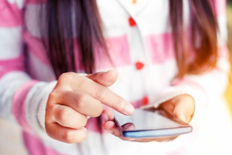 Closeup on teen girls hand using smartphone.