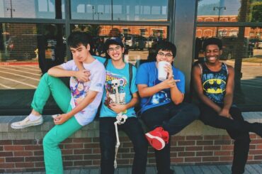Friends sitting on a wall outdoors.