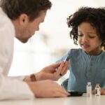 Doctor showing child a vial of vaccine.