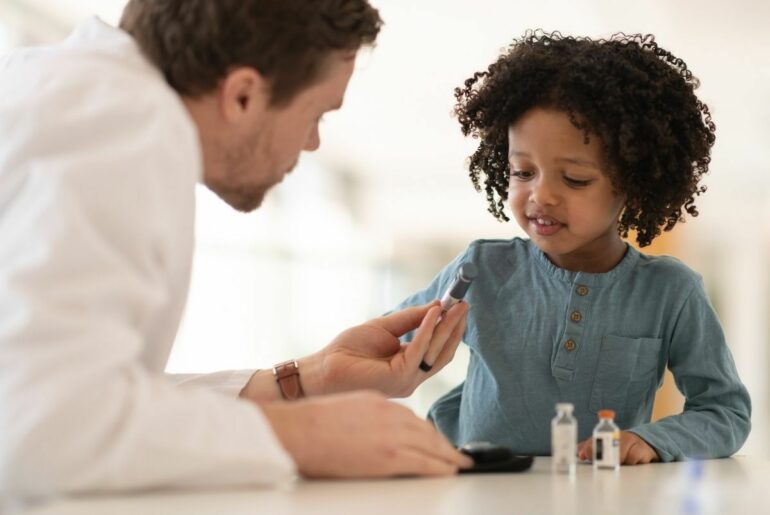 Doctor showing child a vial of vaccine.