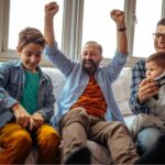 Parents celebrating on couch with two kids.