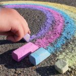 Close up of childs hand drawing a chalk rainbow for LGBTQ Pride.