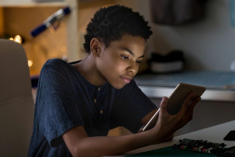 Teen reads on tablet at home.