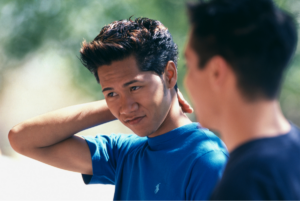 Asian American father and teen son talking.