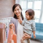 Smiling mom holding toddler while paying for clothes.