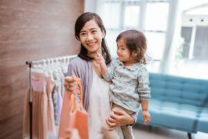 Smiling mom holding toddler while paying for clothes.