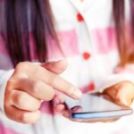 Close up on teen girl's hands as she uses smartphone.