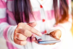 Close up on teen girl's hands as she uses smartphone.