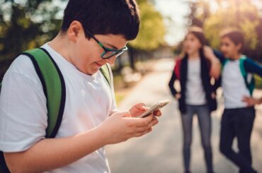 Boy in school yard on smartphone.