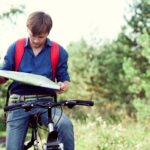 Teen boy on bike looking at a map.