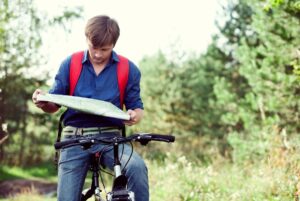 Teen boy on bike looking at a map.