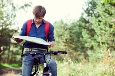 Teen boy on bike looking at a map.