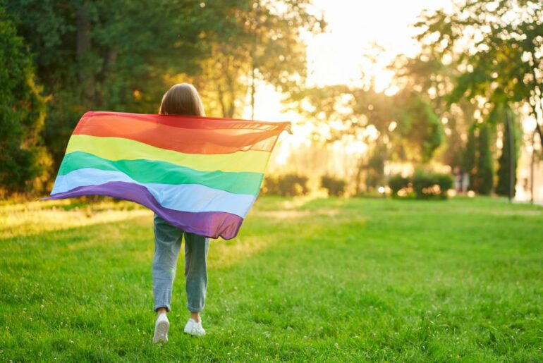 Kid with rainbow pride flag. A parent's guide to supporting LGBTQ+ kids.