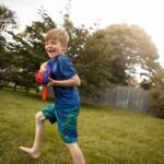 Boy playing with toy gun outdoors.